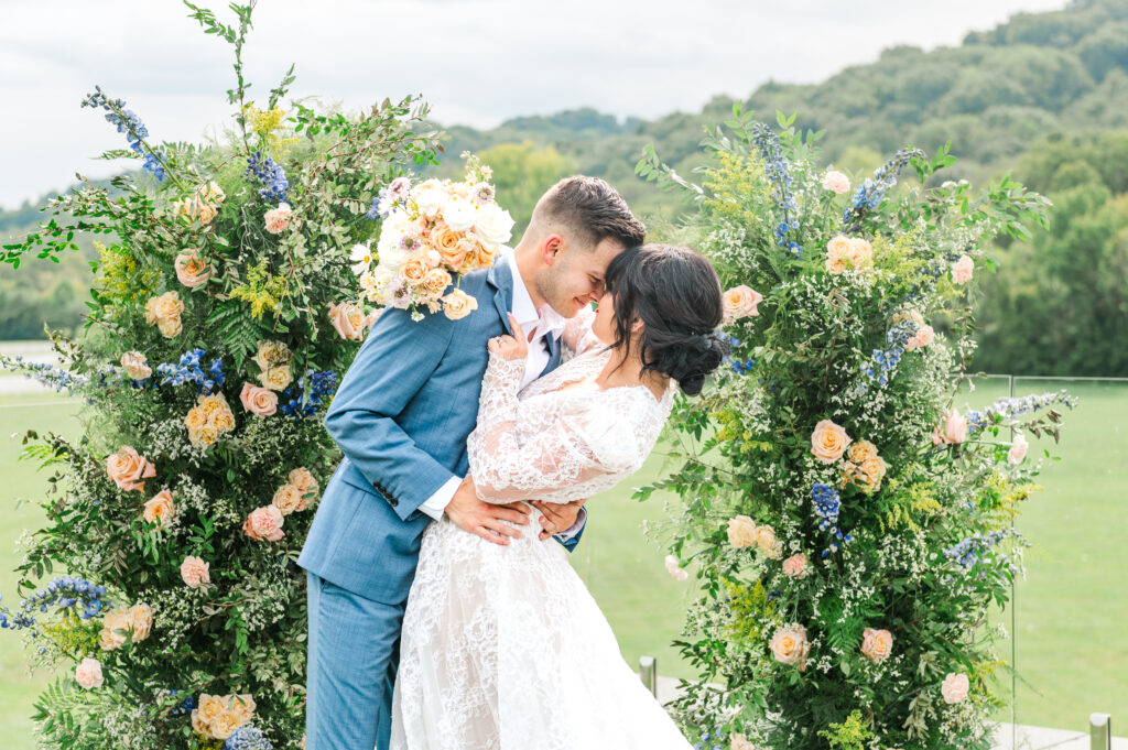 Lexington bride and groom kissing with stunning floral arch and vibrant bouquet